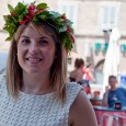 Concetta “Titti” Carraturo is the center of attention today. She wears a stylish white peplum top, fitted black pants, matching heels, and a smile. Occasionally her hand reaches up to gingerly touch the laurel wreath with red ribbons resting on her head. 