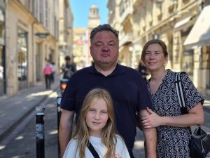 A man, a woman and a 10-year-old girl stand in the main public square in Arles.
