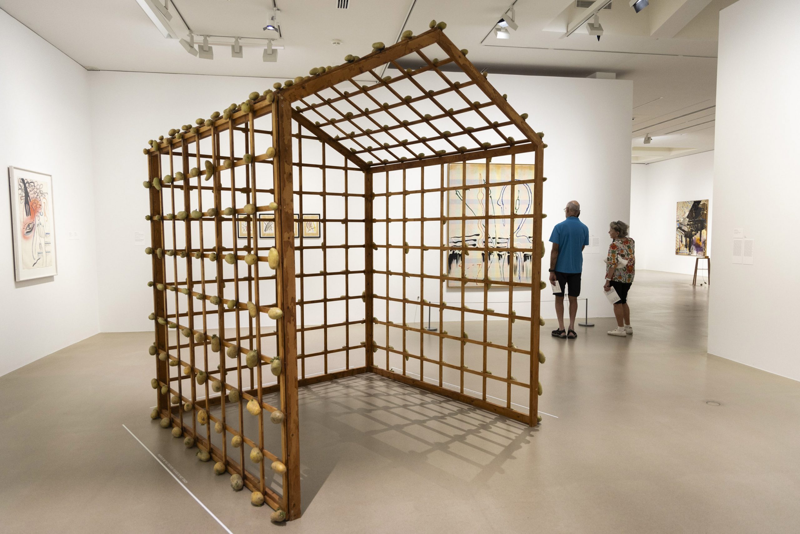 A wooden frame structure with potatoes attached stands in a museum.