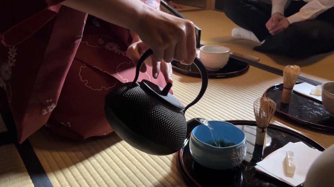 Nao Fujimoto pours water into a guest’s chawan, inviting them to whisk the tea themselves during a tea ceremony at Onishi Tsune Shoten. Photo taken by Angeles Maku.