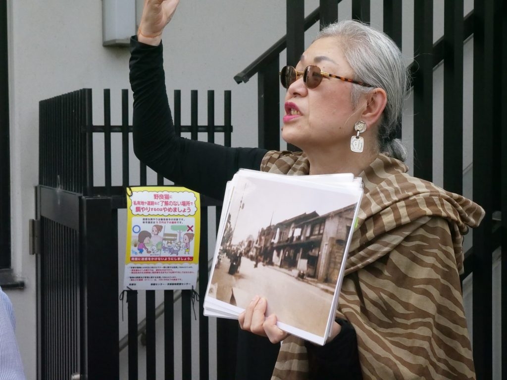 A woman hold up a picture showing what the Sujin neighborhood used to look like.