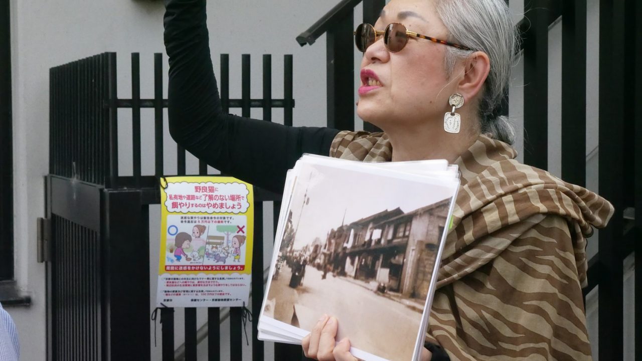 A woman hold up a picture showing what the Sujin neighborhood used to look like.