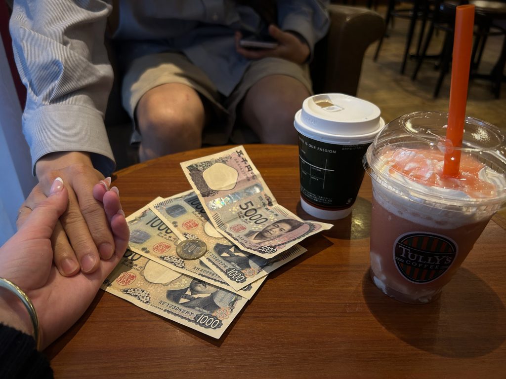 Money on a cafe table, with drinks. Two hands clapsed