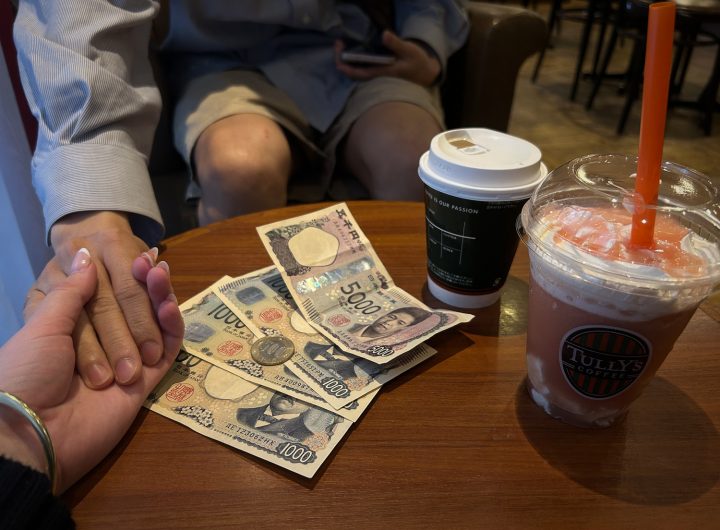 Money on a cafe table, with drinks. Two hands clapsed