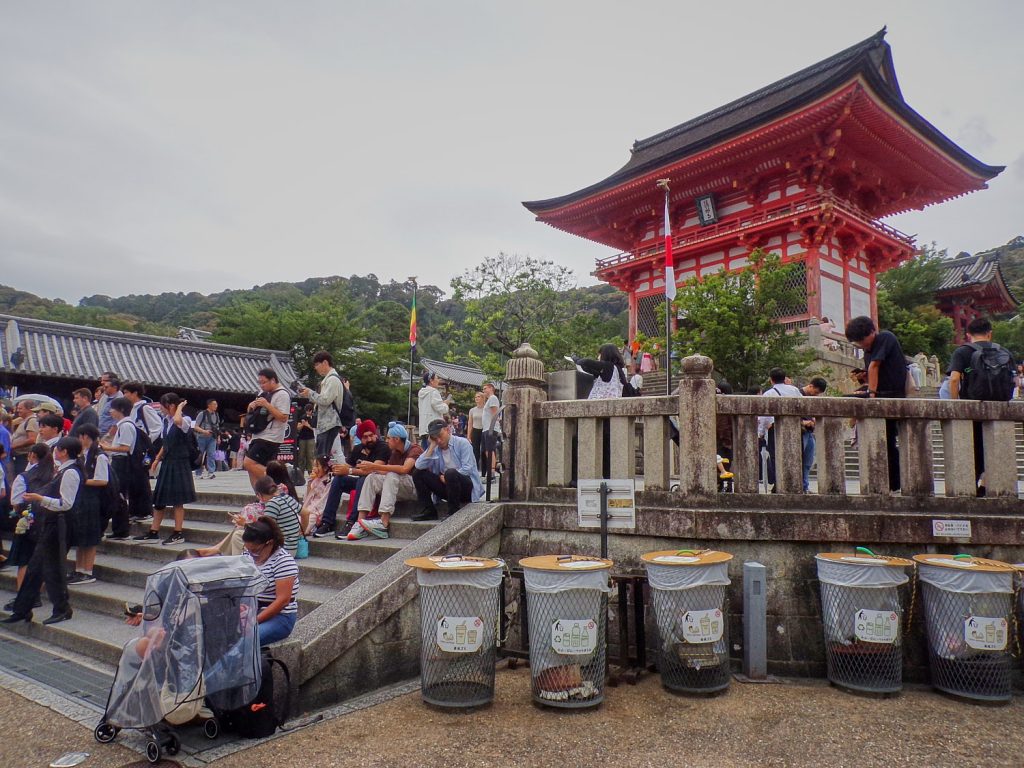 People sit on low calls along a stair to a temple.