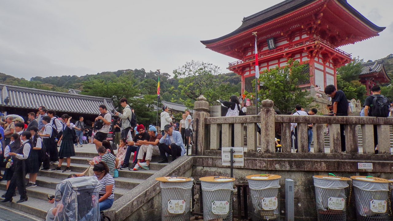 People sit on low calls along a stair to a temple.