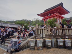 People sit on low calls along a stair to a temple.