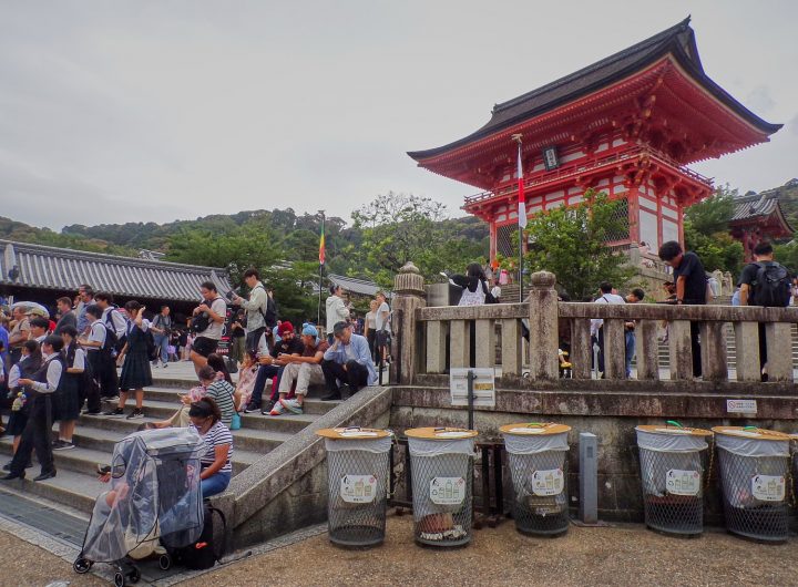 People sit on low calls along a stair to a temple.