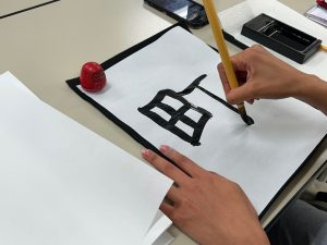 A hand writes a character in Japanese calligraphy