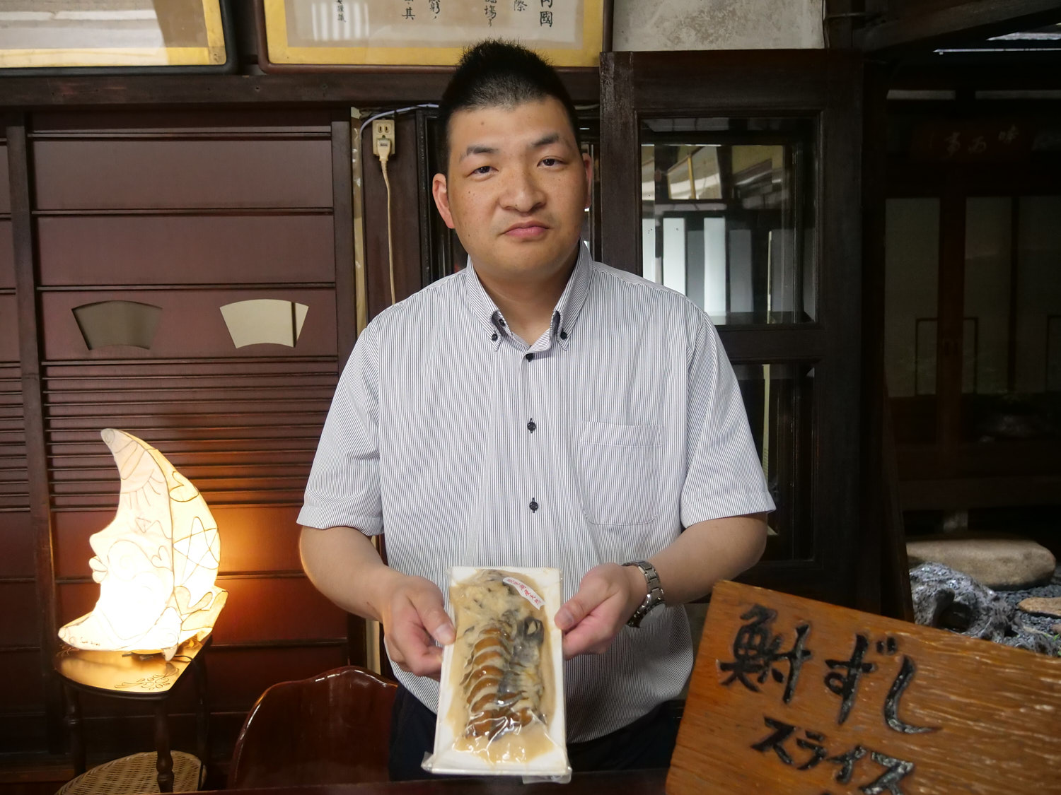 Shintarou Uchida, owner of Sakamoto-ya, a funazushi manufacturer in Otsu, Shiga Prefecture, holds out a package of funazushi.